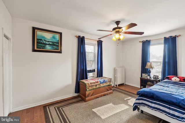 bedroom with hardwood / wood-style floors, radiator heating unit, and ceiling fan