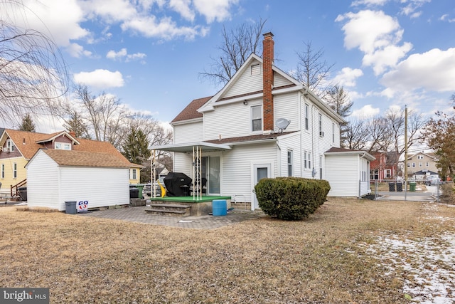 rear view of property featuring a patio, an outbuilding, and a lawn