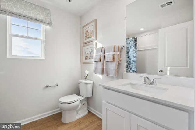 bathroom with hardwood / wood-style flooring, vanity, walk in shower, and toilet