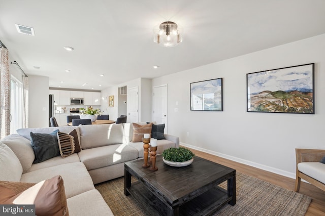 living room with hardwood / wood-style flooring and a notable chandelier