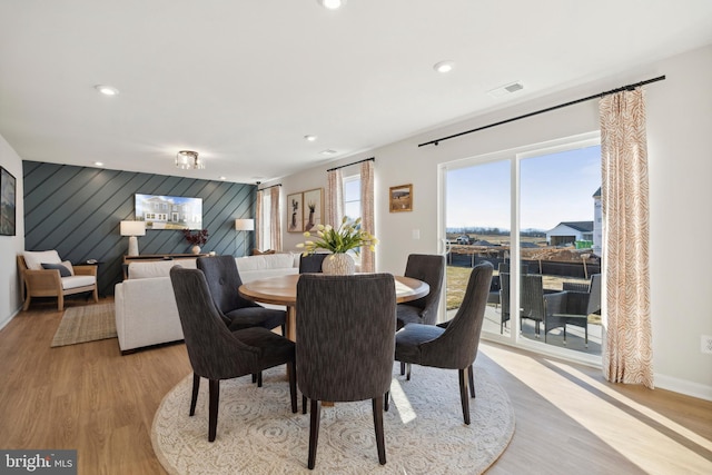 dining room with light hardwood / wood-style flooring and wood walls