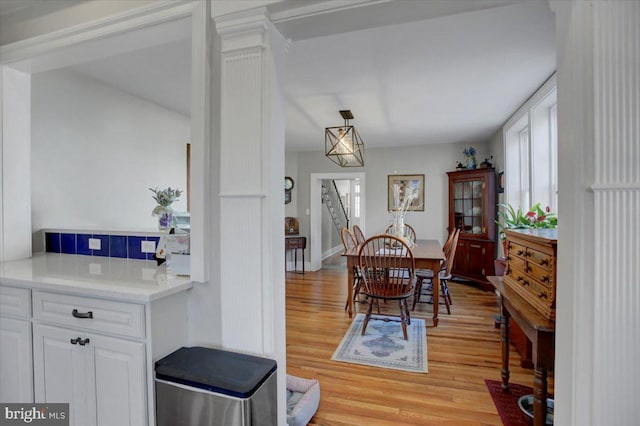 dining room featuring decorative columns and light wood-type flooring