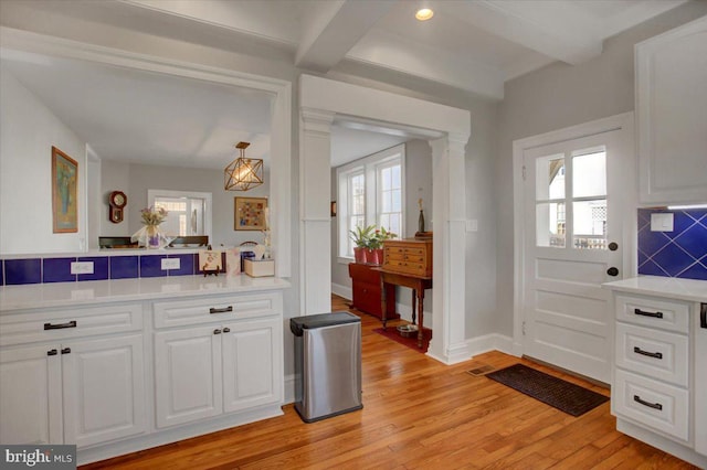 interior space with decorative backsplash, beamed ceiling, white cabinets, and light wood-type flooring