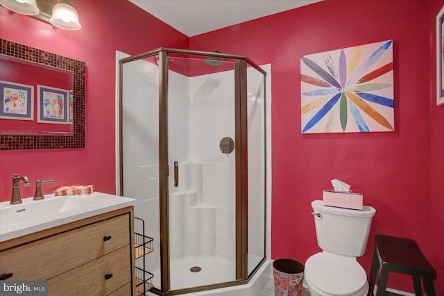 bathroom featuring toilet, vanity, and a shower with shower door