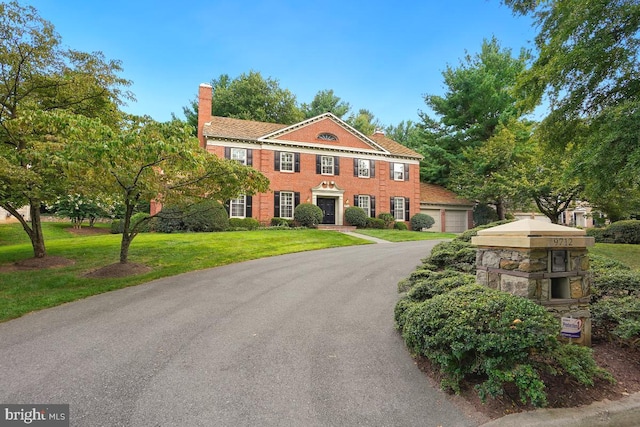 colonial house featuring a garage and a front yard