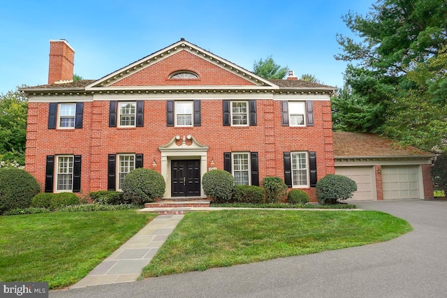 colonial house featuring a garage and a front yard