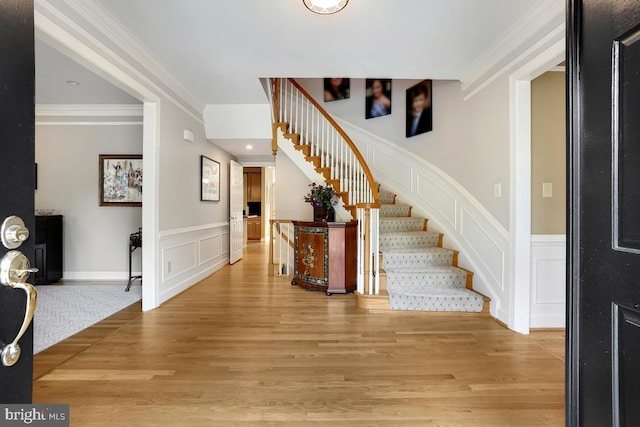 foyer entrance with crown molding and light hardwood / wood-style flooring