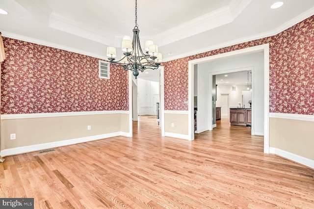 unfurnished dining area featuring hardwood / wood-style floors, crown molding, and a raised ceiling