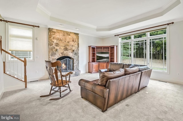 living room with a fireplace, ornamental molding, a tray ceiling, and light carpet