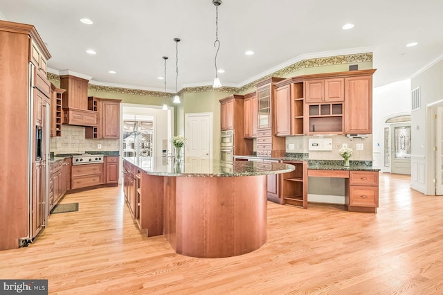 kitchen featuring light hardwood / wood-style flooring, stainless steel appliances, a kitchen island, decorative light fixtures, and dark stone counters