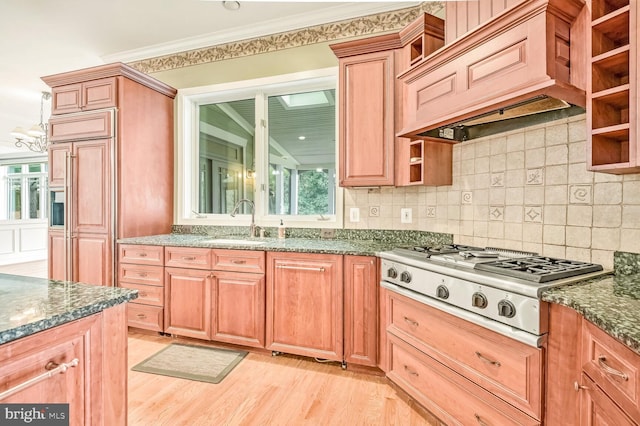 kitchen featuring premium range hood, stainless steel gas stovetop, light wood-type flooring, and dark stone countertops