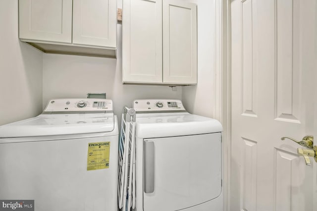 clothes washing area with cabinets and separate washer and dryer