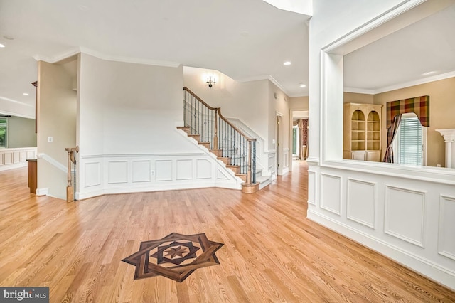 entrance foyer with crown molding and light hardwood / wood-style floors