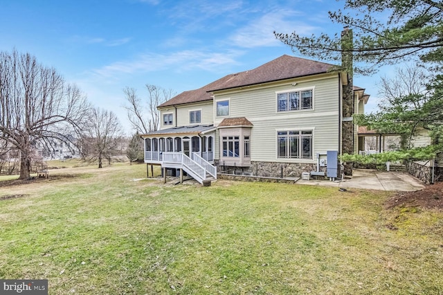 rear view of property featuring a sunroom, a patio area, and a lawn