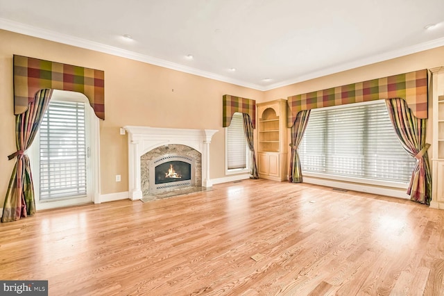 unfurnished living room featuring ornamental molding, a high end fireplace, and light hardwood / wood-style floors