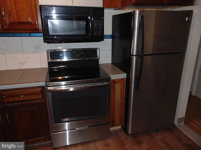 kitchen with appliances with stainless steel finishes, dark wood-type flooring, and decorative backsplash