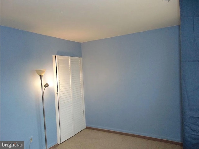 unfurnished bedroom with light colored carpet and a closet