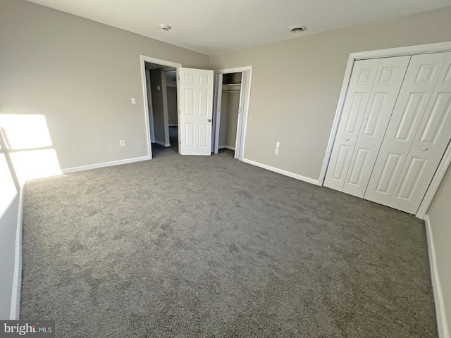 unfurnished bedroom with multiple closets and dark carpet