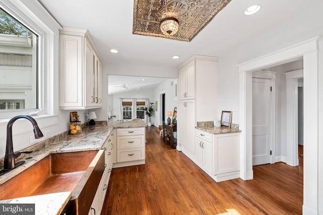 kitchen featuring recessed lighting, a sink, a peninsula, and wood finished floors