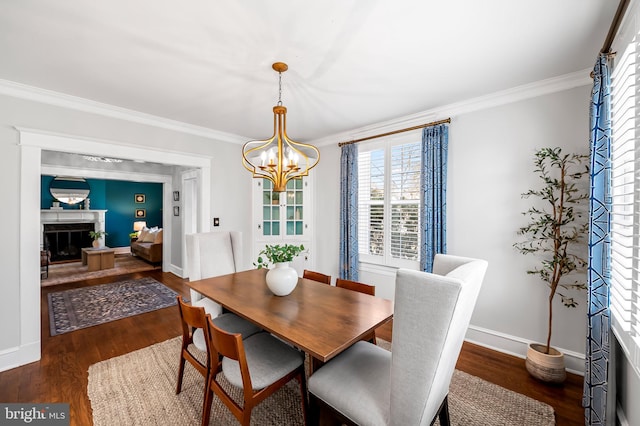 dining space featuring ornamental molding, wood finished floors, a glass covered fireplace, and an inviting chandelier