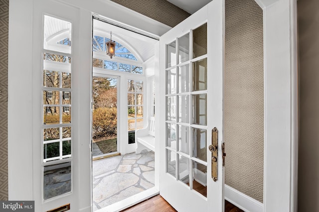 doorway with wood finished floors, french doors, baseboards, and wallpapered walls