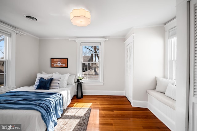 bedroom featuring multiple windows, ornamental molding, and hardwood / wood-style floors