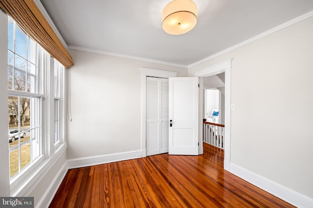 spare room featuring a wealth of natural light, baseboards, dark wood-type flooring, and ornamental molding