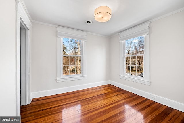 unfurnished bedroom with baseboards, visible vents, hardwood / wood-style floors, and ornamental molding