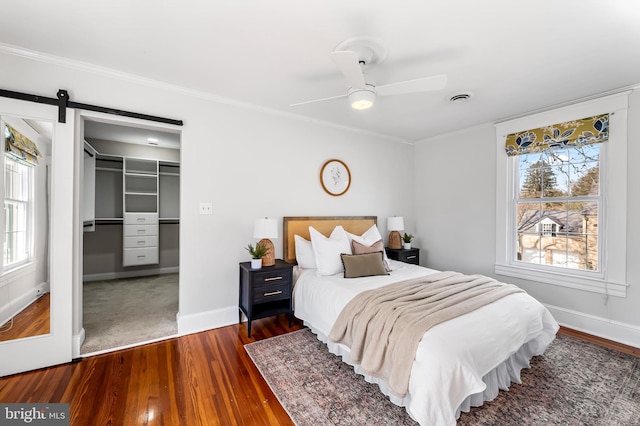 bedroom with crown molding, visible vents, dark wood finished floors, and a barn door