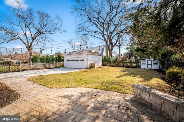 view of yard featuring a garage, a fenced backyard, and an outbuilding