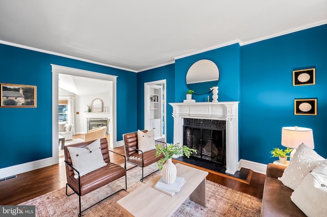 living room featuring wood finished floors, visible vents, baseboards, and a premium fireplace