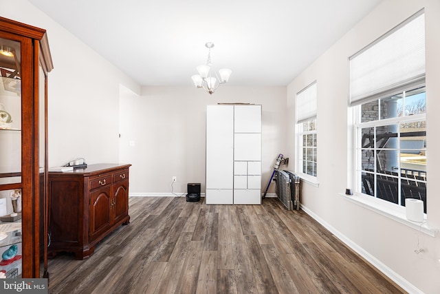 spare room with an inviting chandelier and dark hardwood / wood-style floors