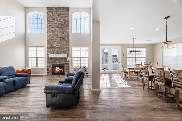 living room featuring hardwood / wood-style flooring, a stone fireplace, and a towering ceiling