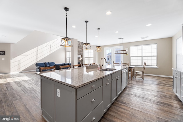 kitchen featuring hanging light fixtures, sink, a center island with sink, and gray cabinets