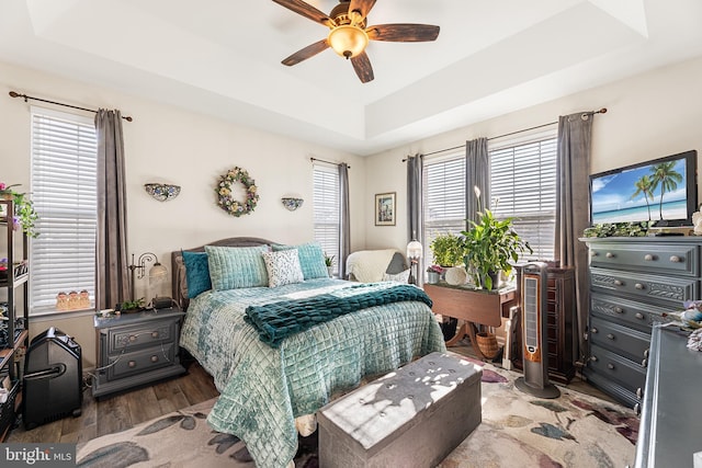 bedroom with dark hardwood / wood-style floors, a raised ceiling, and ceiling fan