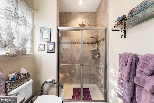 bathroom featuring a shower with shower door and toilet