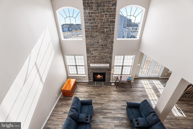 living room with wood-type flooring, a large fireplace, and a towering ceiling