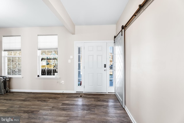 entrance foyer with dark wood-type flooring, a barn door, and beam ceiling