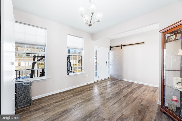 interior space with a barn door, dark hardwood / wood-style flooring, and a notable chandelier