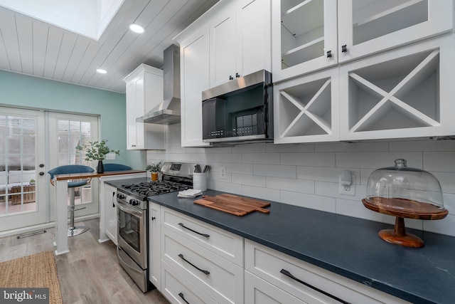 kitchen featuring white cabinetry, backsplash, wall chimney exhaust hood, and appliances with stainless steel finishes