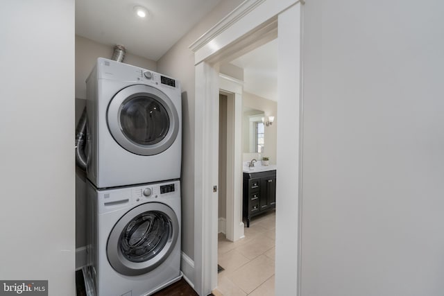 laundry area featuring stacked washer and clothes dryer and light tile patterned floors