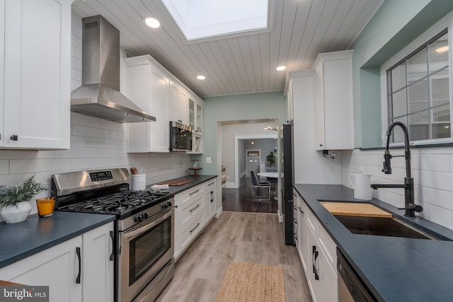 kitchen with white cabinetry, sink, wall chimney exhaust hood, and appliances with stainless steel finishes