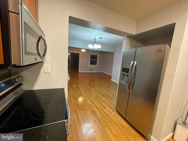 kitchen with hanging light fixtures, a notable chandelier, stainless steel appliances, and light wood-type flooring