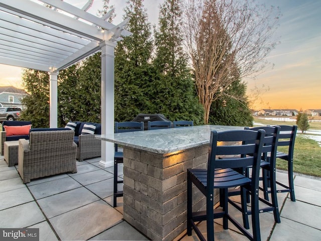 patio terrace at dusk featuring outdoor lounge area, a pergola, and a bar