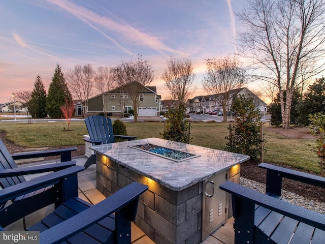 patio terrace at dusk featuring a yard and an outdoor fire pit