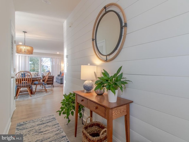 corridor with light hardwood / wood-style flooring and wood walls