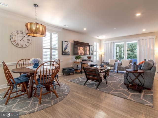 dining area featuring crown molding, wood-type flooring, and plenty of natural light