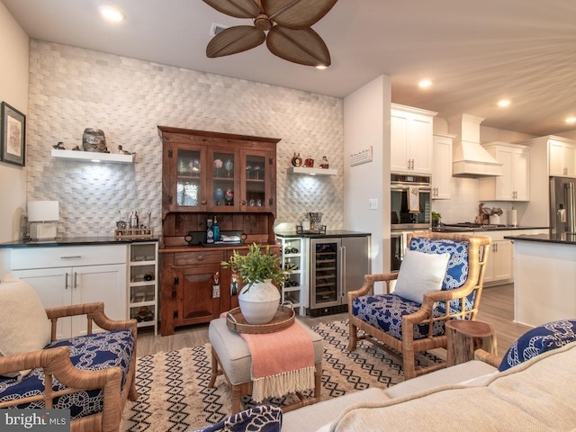 living room featuring ceiling fan, bar, wine cooler, and light wood-type flooring