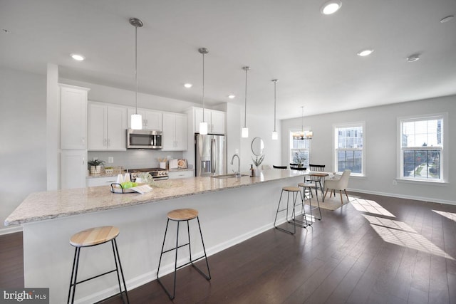 kitchen featuring stainless steel appliances, white cabinetry, a large island, and a breakfast bar