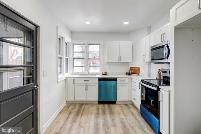 kitchen with sink, stainless steel appliances, tasteful backsplash, white cabinets, and light wood-type flooring